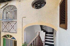 A building with a staircase, a window with a metal grille, and a door with a geometric pattern.