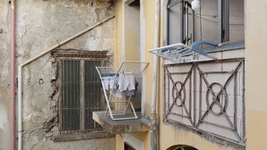 Un balcone con uno stendibiancheria e una finestra con inferriata in metallo.