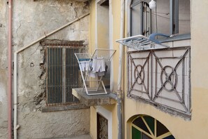 A balcony with a clothes drying rack and a window with a metal grill.