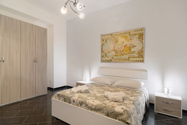 A bedroom with a bed, nightstands, a wardrobe, and a ceiling light fixture.
