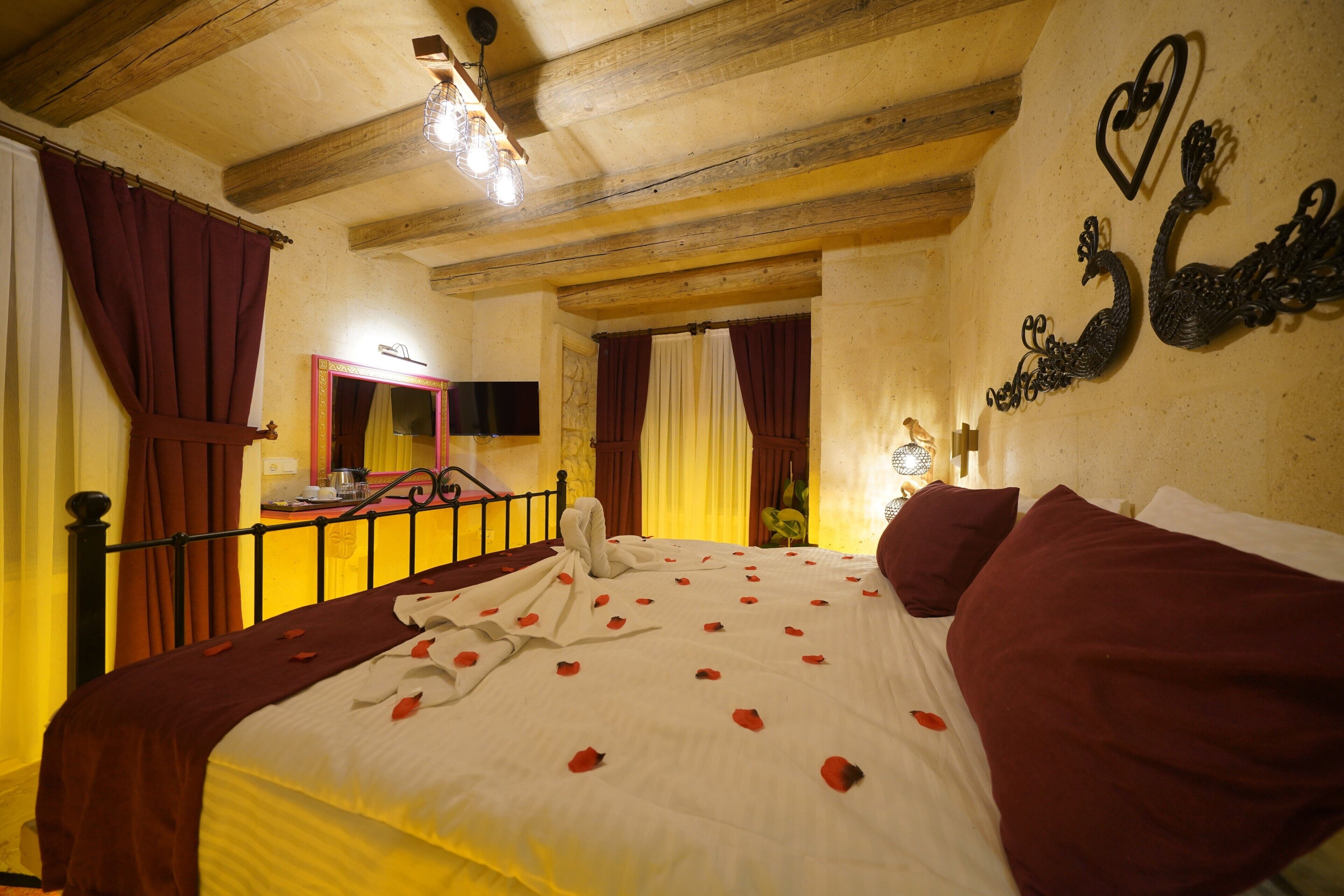 A hotel room with a bed, curtains, a television, and a decorative wall piece.