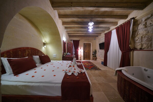 Una habitación de hotel con una cama grande, una bañera y una pared de piedra.