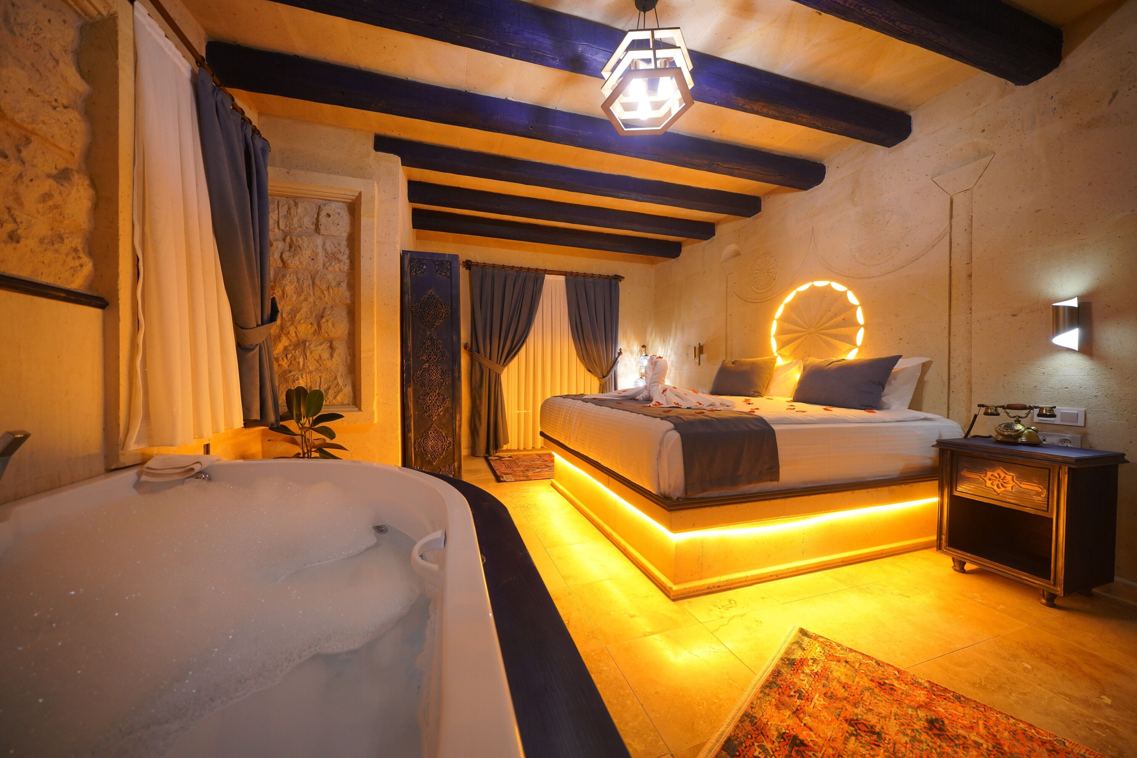 A room with a large bed, a bathtub, and a wall-mounted light fixture.