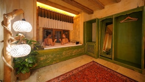 A room with a bathtub, a mirror, a hanging light fixture, and a green door. - Uçhisar Palace in Cappadocia Hotel (Nevsehir)