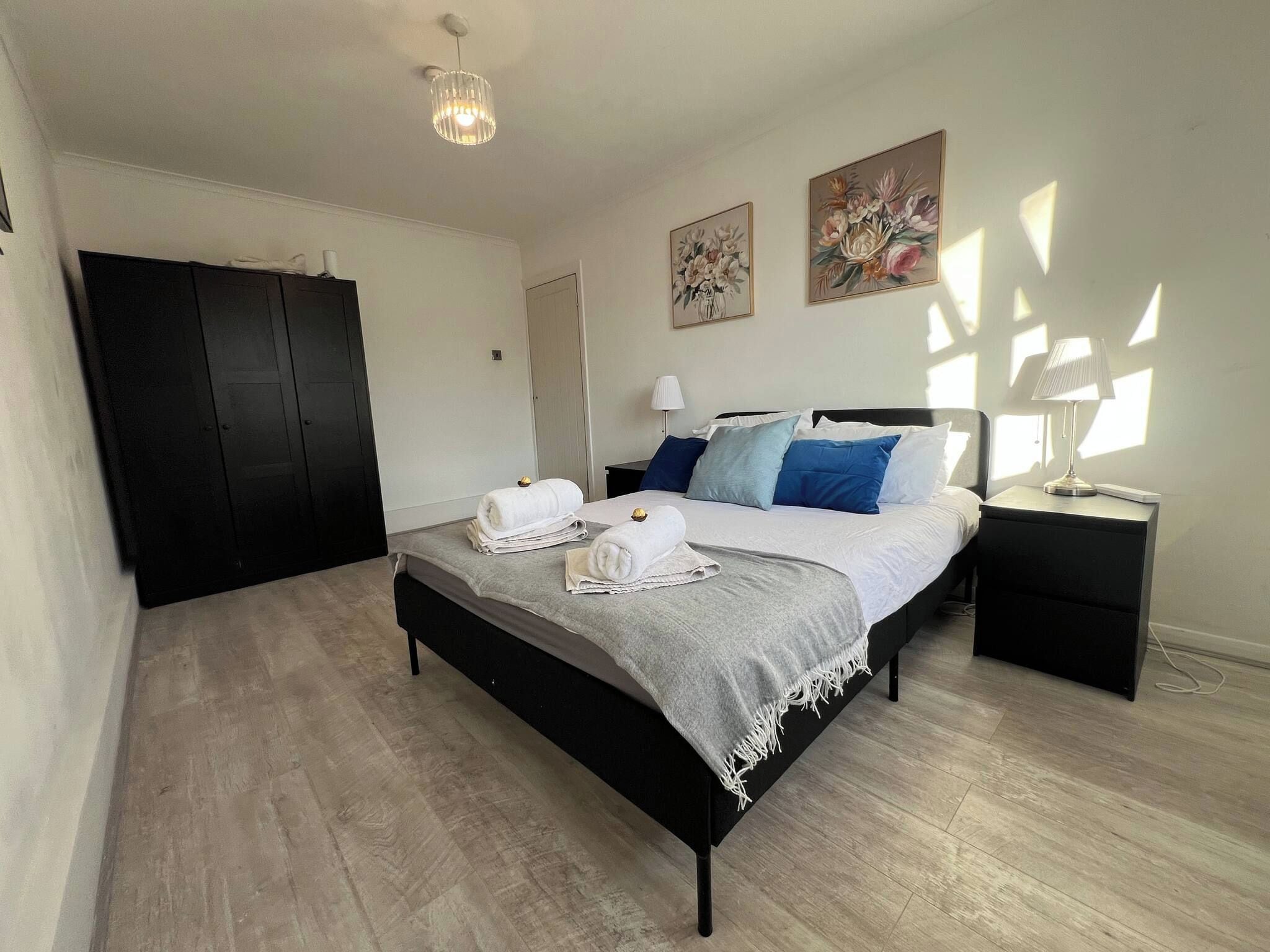A bedroom with a bed, bedside tables, a wardrobe, and artwork on the walls.
