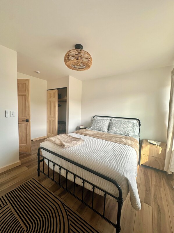 A bedroom with a bed, bedside table, and a hanging light fixture.