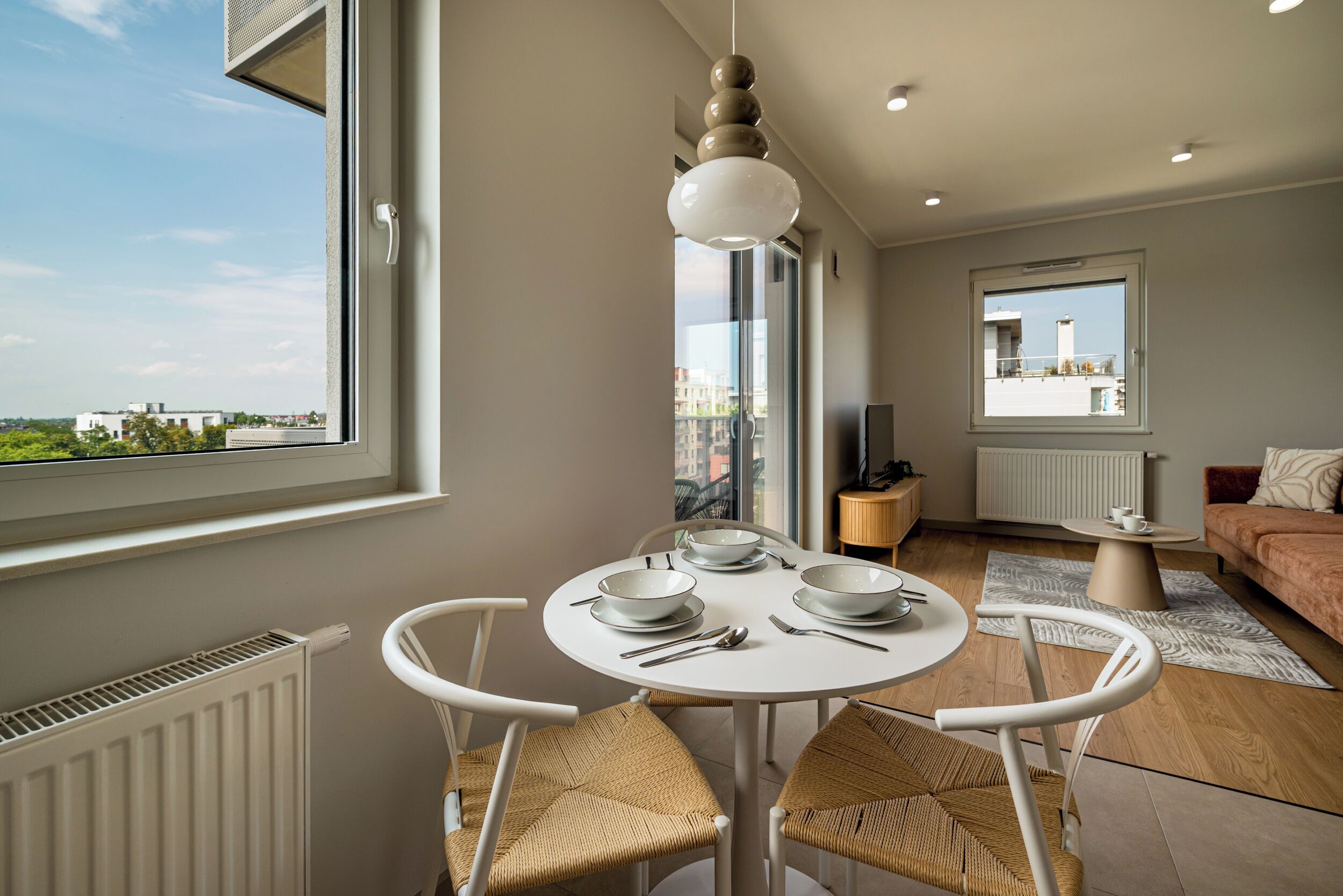 Una sala de estar moderna con comedor, ventanas amplias y vista a la ciudad.