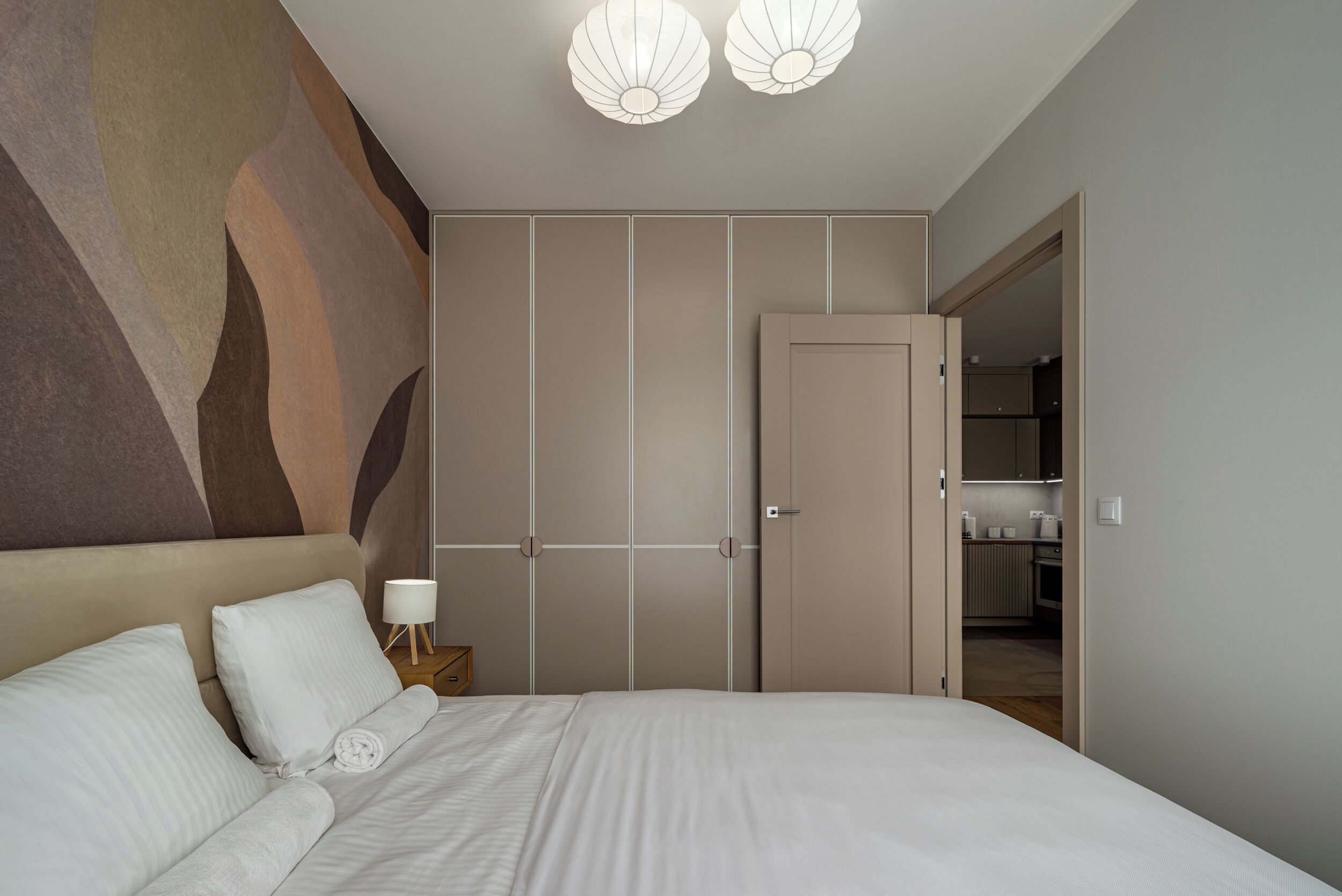 Ein Schlafzimmer mit einem großen Bett, einem Nachttisch, einer Wandlampe und einem Kleiderschrank.