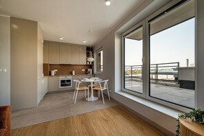 A modern kitchen with a dining area, large windows, and a view of the cityscape. - RentPlanet - Apartament Braterska (Wrocław)