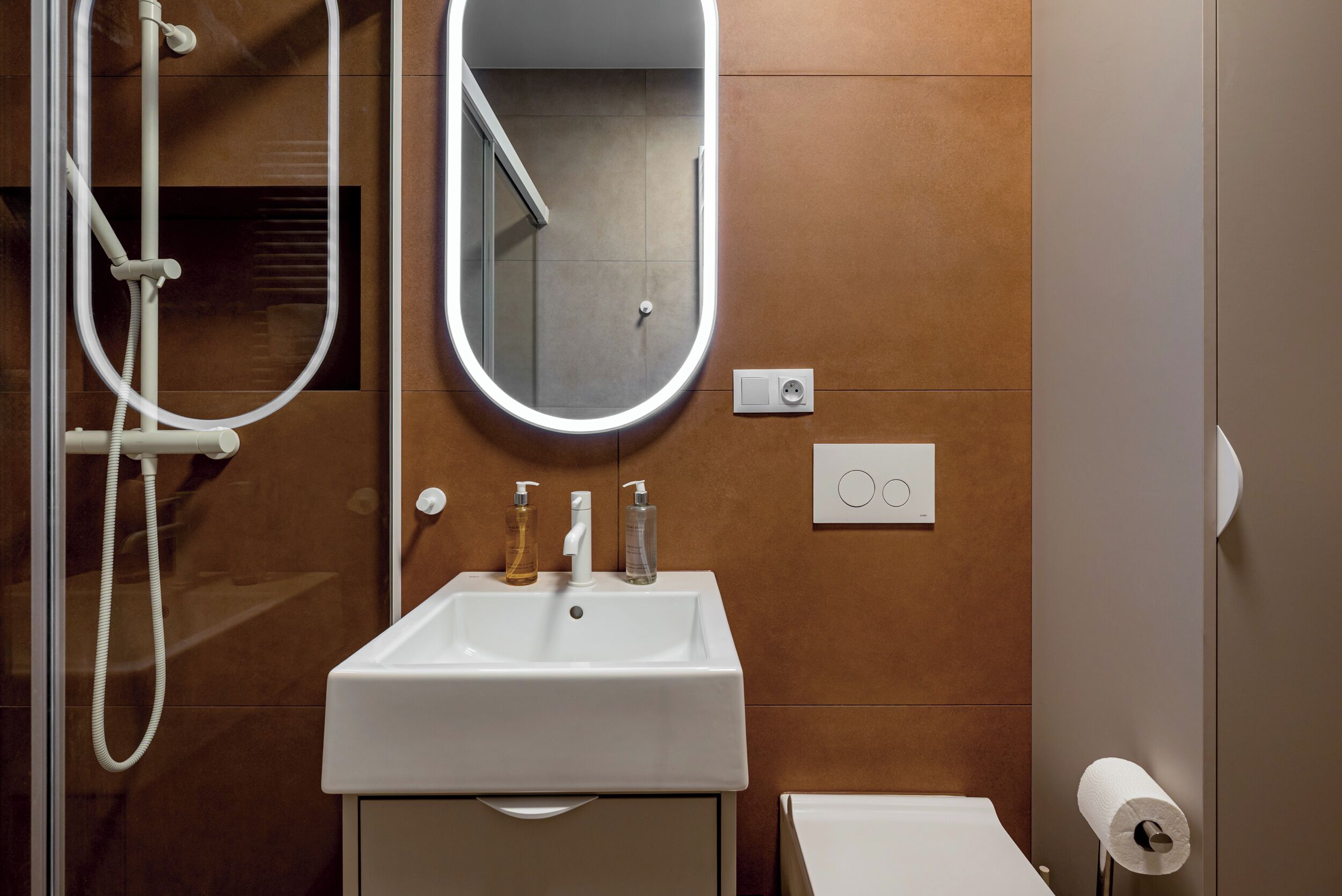 Ein Badezimmer mit weißem Waschbecken, einem Spiegel, einer Dusche und einer Toilette.