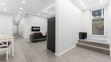 A modern interior with a hallway leading to a living area, a flat-screen TV, and a window with a view.