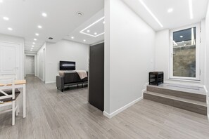 Ein modernes Interieur mit einer Diele, die in einen Wohnbereich führt, einem Flachbildfernseher und einem Fenster mit Aussicht.
