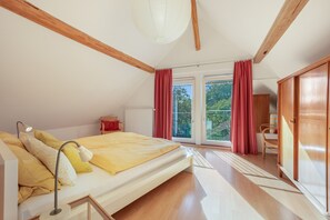 A bedroom with a bed, a desk, a chair, a radiator, and a window with curtains. - Vacation home 'am quittenbaum', family vacation on Lake Constance (Überlingen)