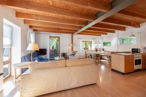 A spacious living area with a sofa, a dining table, and a kitchen area with a microwave and oven. - Vacation home 'am quittenbaum', family vacation on Lake Constance (Überlingen)