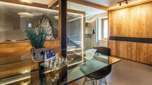 A modern interior with a glass table, a chess set, and a wooden accent wall. - Petit Reins - Alpine Lodge close to Ski Return (Valtournenche)