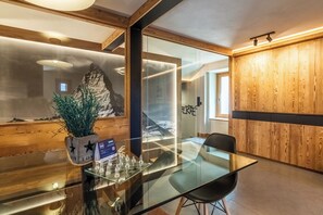 A modern interior with a glass table, a chess set, and a wooden accent wall. - Petit Reins - Alpine Lodge close to Ski Return (Valtournenche)