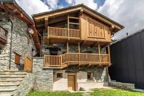 Un bâtiment en pierre de deux étages, doté de balcons en bois et d’une façade en pierre.