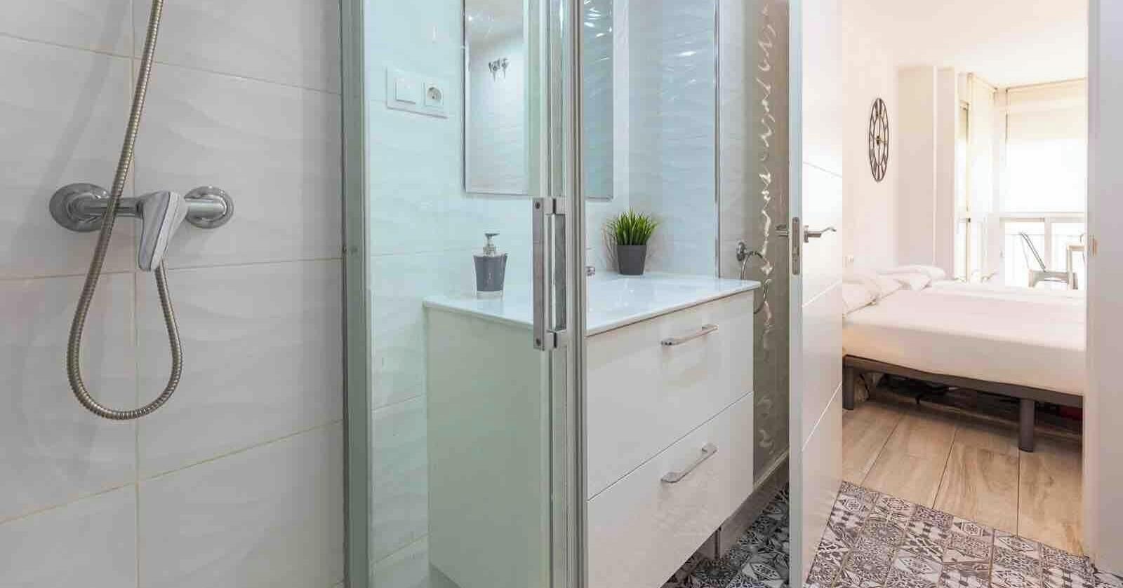 A bathroom with a glass shower enclosure, a white sink, and a mirror.