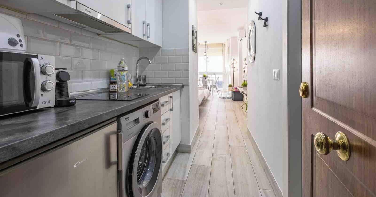 Una cocina moderna con lavadora integrada, microondas y pileta.