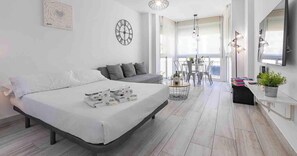 Una habitación de hotel moderna con una cama, un sofá, una mesa de comedor y un televisor.
