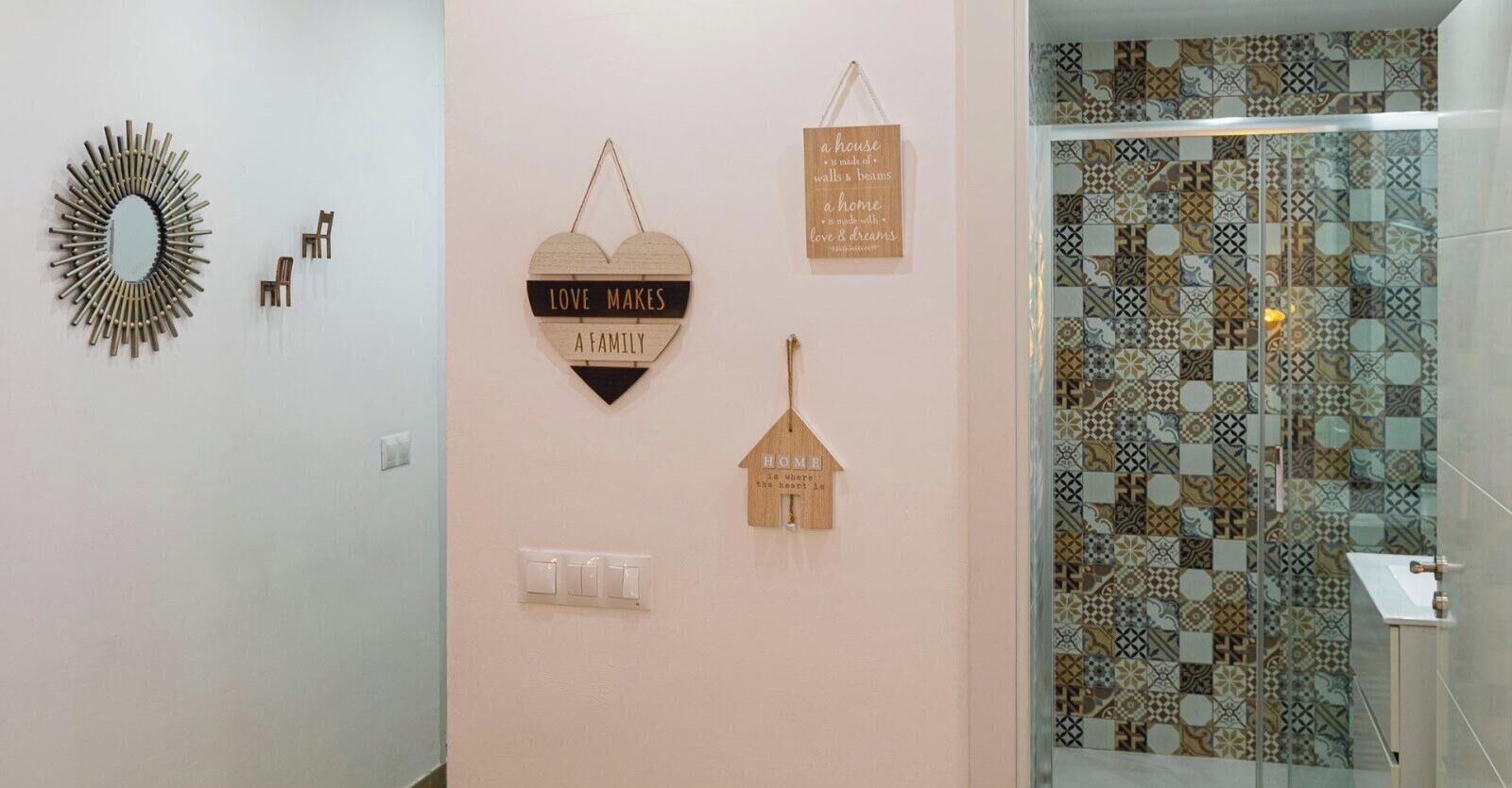Un baño con pared de azulejos estampados, un espejo con diseño de sol y interruptores de luz en la pared.