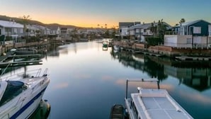 Un puerto deportivo con barcos amarrados, agua tranquila y edificios residenciales al fondo.