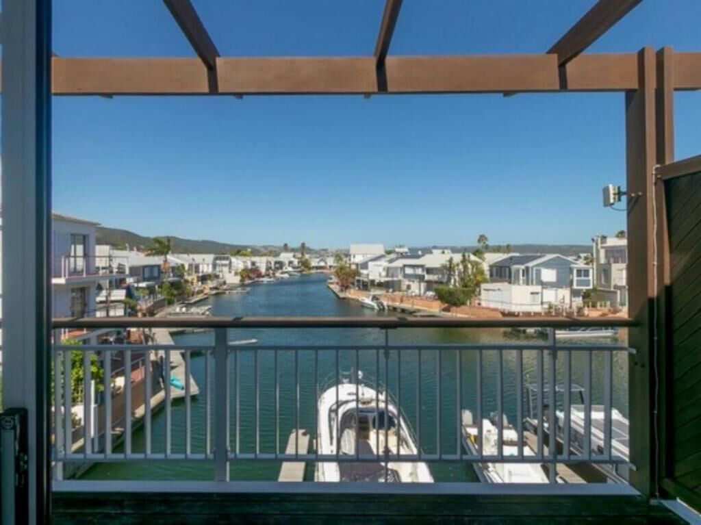 A balcony with a view of a canal, boats, and a residential area.