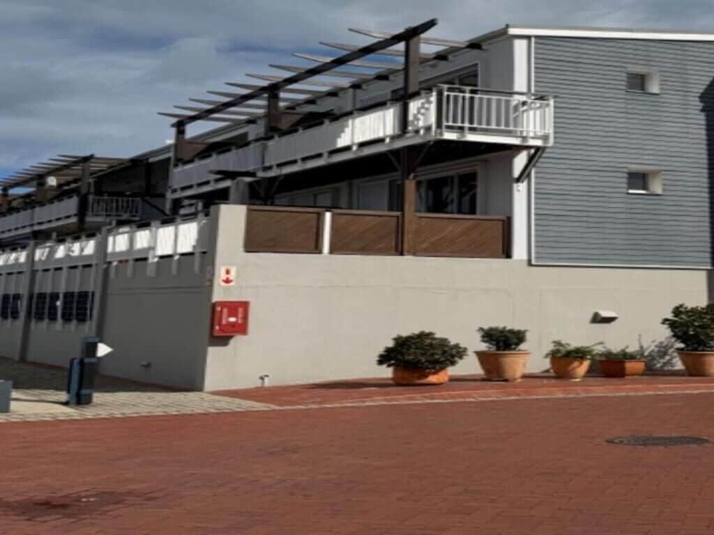 Un edificio con techo plano, balcón e hidrante.
