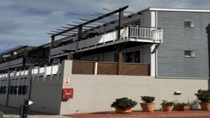 Un edificio con techo plano, balcón e hidrante.