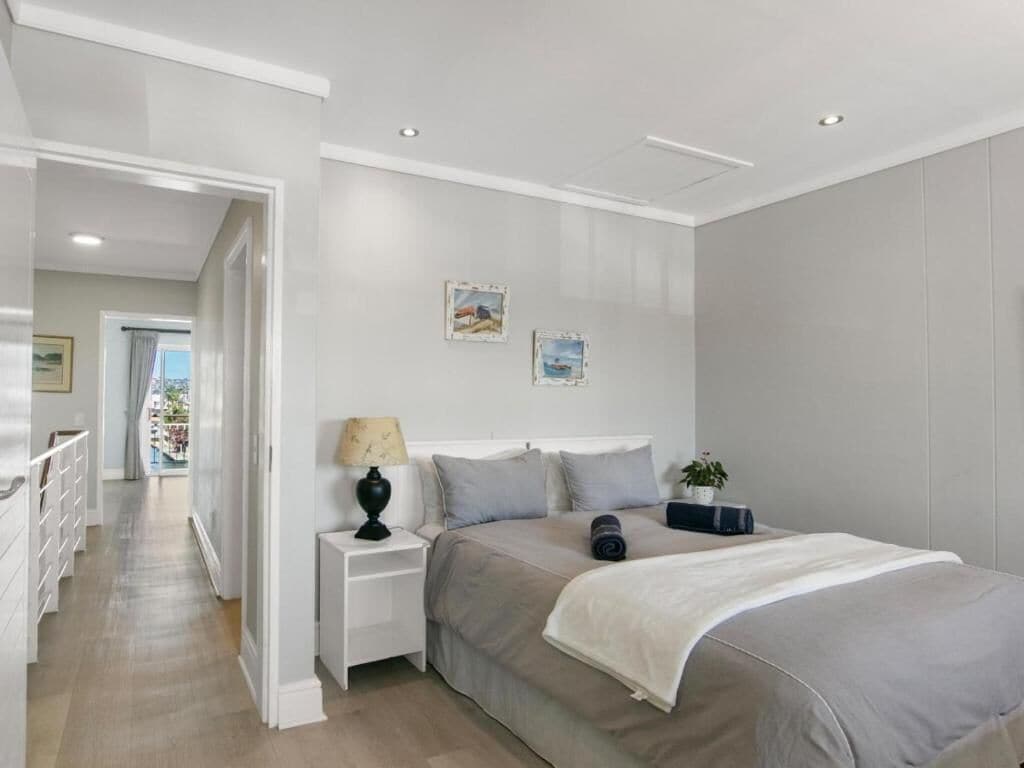 Un dormitorio moderno con una cama grande, mesitas de noche y vistas a otra habitación.