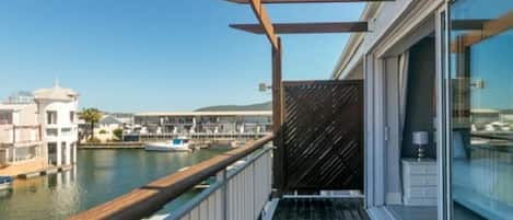 A balcony with a view of a marina and buildings across the water.