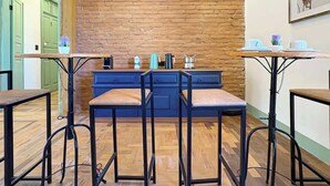 Un café acogedor con suelo de madera, pared de ladrillo y mostrador azul con taburetes.