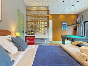 Une chambre d’hôtel équipée d’un lit, d’une table de billard, d’un minibar et offrant une vue sur l’extérieur.