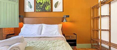 A hotel room with a bed, a nightstand, a lamp, and a wooden ladder.