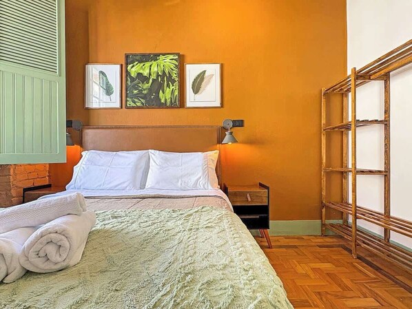 A hotel room with a bed, a nightstand, a lamp, and a wooden ladder.