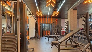 Ein Fitnessstudio mit Krafttrainingsgeräten, Bänken und Kurzhanteln.