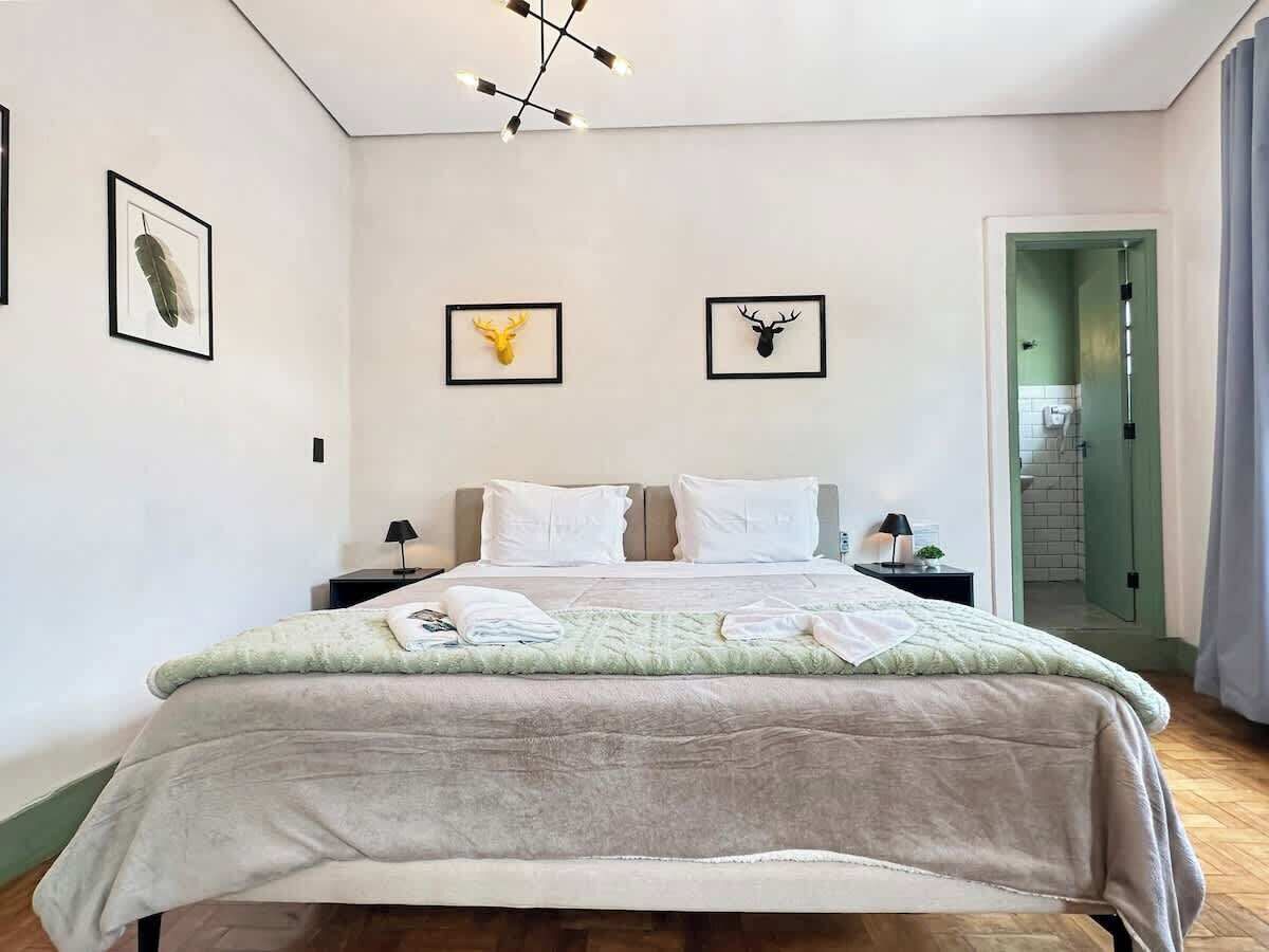 Ein Schlafzimmer mit einem Bett, Nachttischen, einer Lampe und zwei gerahmten Tierköpfen an der Wand.
