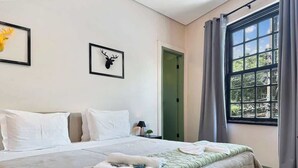 A hotel room with a bed, a door, and a window with curtains. - Villa_Aberdeen _01 · Villa Aberdeen | Wi-Fi | Central | Garagem, Qua... (Campos do Jordão)