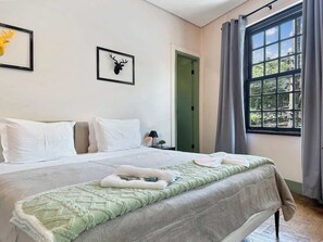 Una camera d'albergo con un letto, una porta e una finestra con tende.