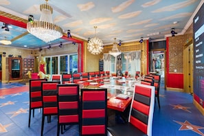 A dining area with a large round table, red and black chairs, and chandeliers. - Last Minute Disney! Private Pool, Hot Tub, Game Room & Themed Bedrooms. Book Now! #54851 (Orlando)