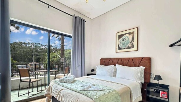 Une chambre avec un grand lit, une table de chevet, une fenêtre donnant sur un beau paysage et un fauteuil près de la fenêtre.