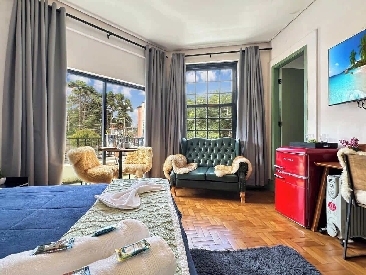 Een hotelkamer met een bed, een slaapbank, een eettafel, een rode apparatuur en een televisie aan de muur.