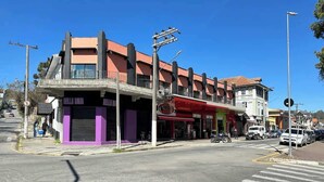Vista de la calle con un edificio que tiene locales comerciales en la planta baja y viviendas en los pisos superiores.