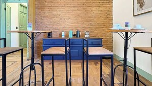 A kitchen area with a brick wall, wooden flooring, and bar stools.