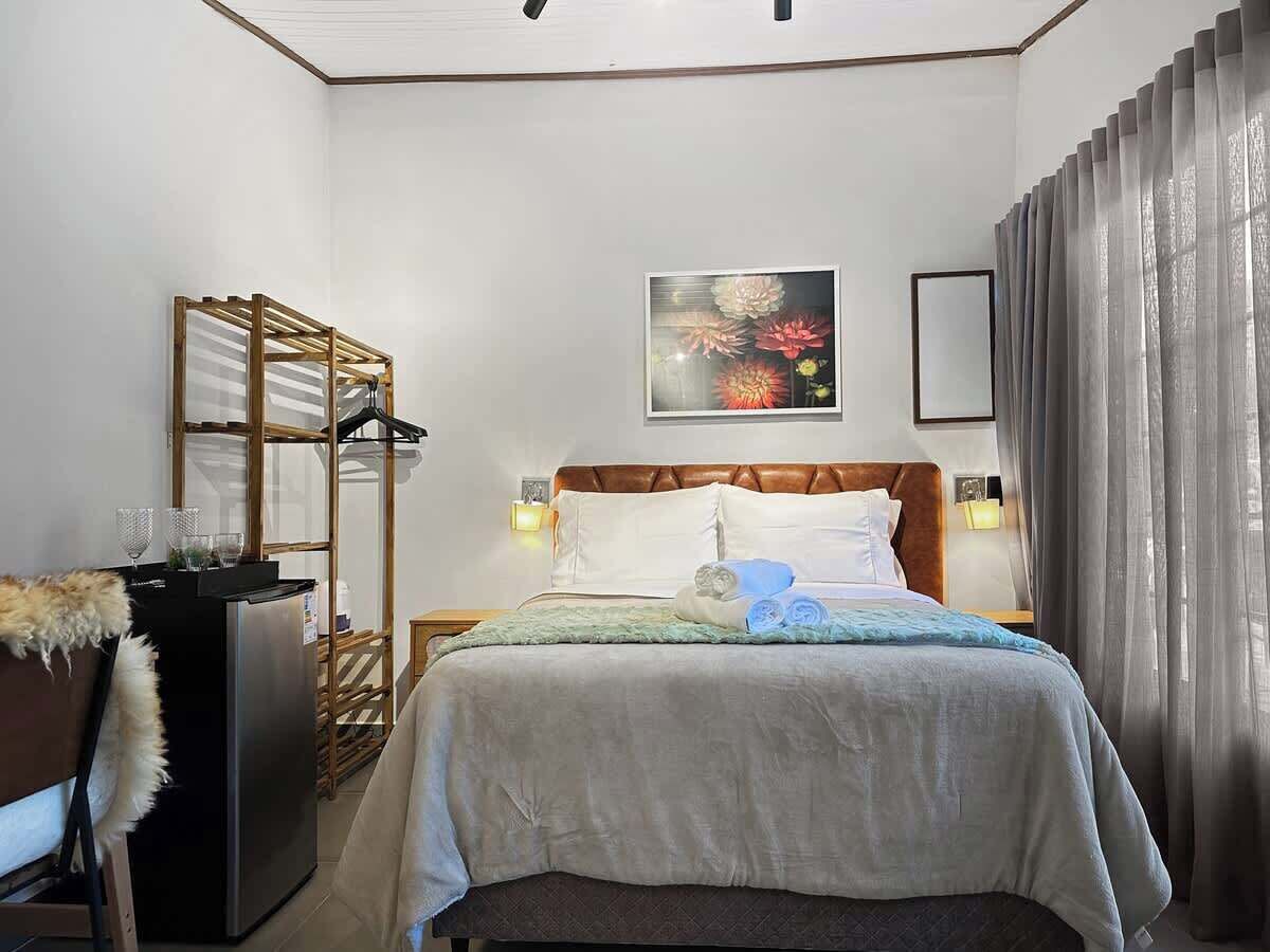 Ein Hotelzimmer mit Bett, Schrank, Schreibtisch mit Computer und Fenster mit Vorhängen.