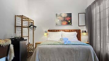 Ein Hotelzimmer mit Bett, Schrank, Schreibtisch mit Computer und Fenster mit Vorhängen.