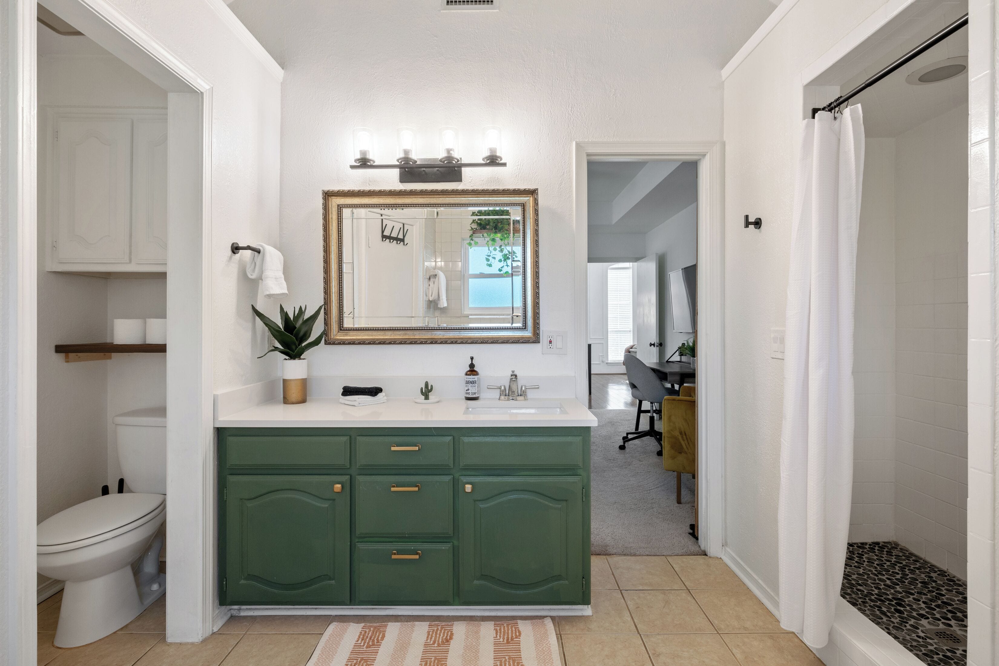 Un bagno con un water bianco, una toeletta verde e uno specchio sopra il lavandino.