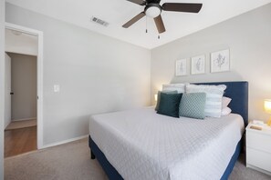 A bedroom with a bed, a ceiling fan, a nightstand, and framed botanical prints on the wall. - Steps from Main street, Updated Family-Friendly Home with Fireplace and Garage! (Frisco)
