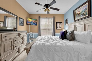 A bedroom with a bed, a dresser, a chair, a ceiling fan, and artwork on the walls. - Last Minute Disney Getaway! Themed Bedrooms & Private Balcony. Book Now! #98463 (Orlando)