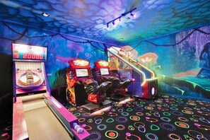 Eine Spielhalle mit Neonlichtern und einem Wandgemälde von einer Meereslandschaft.